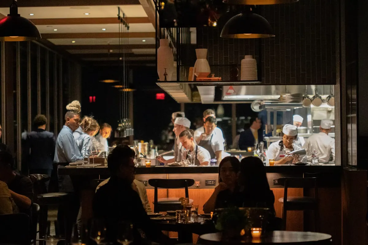 A lively open-kitchen dining room at night