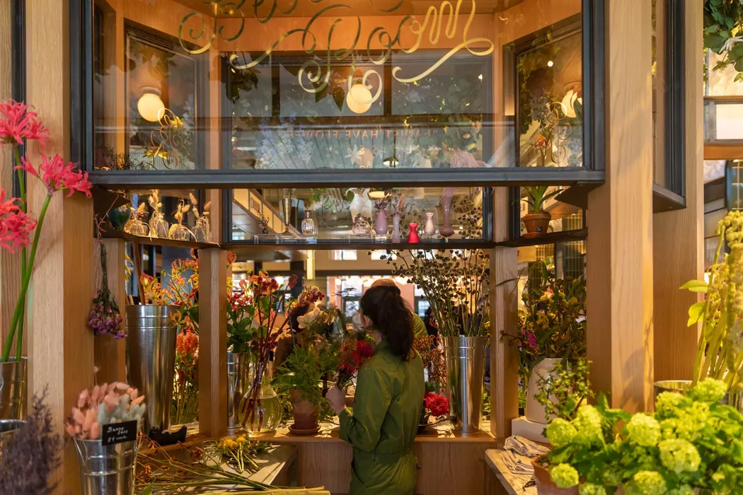 A florist arranging flowers in a warm, plant-filled market