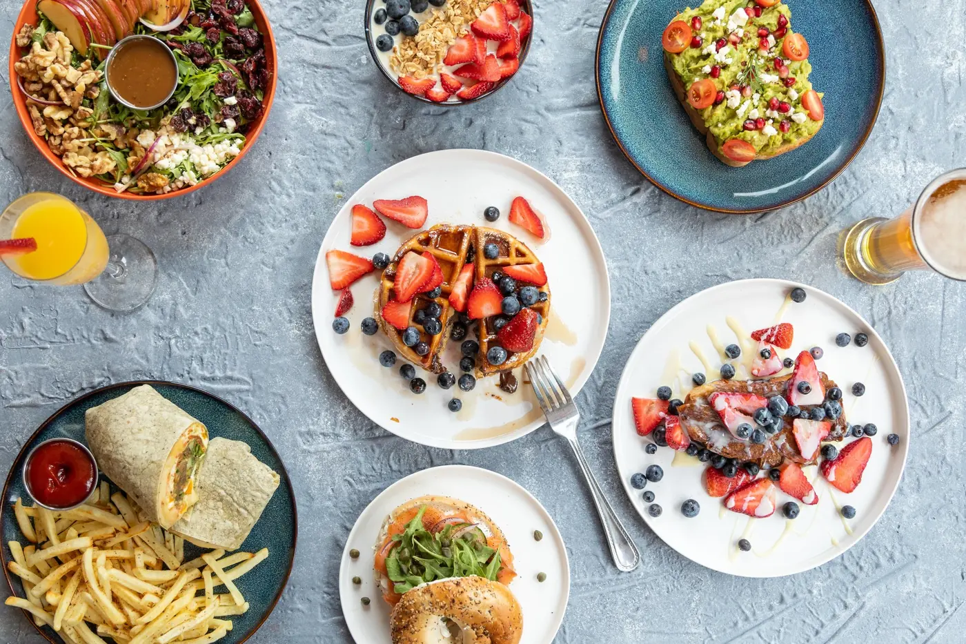 An overhead spread of brunch dishes, fresh fruit and drinks