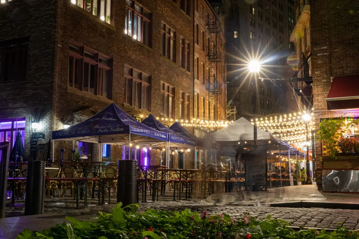 Outdoor dining under string lights on historic Stone Street at night