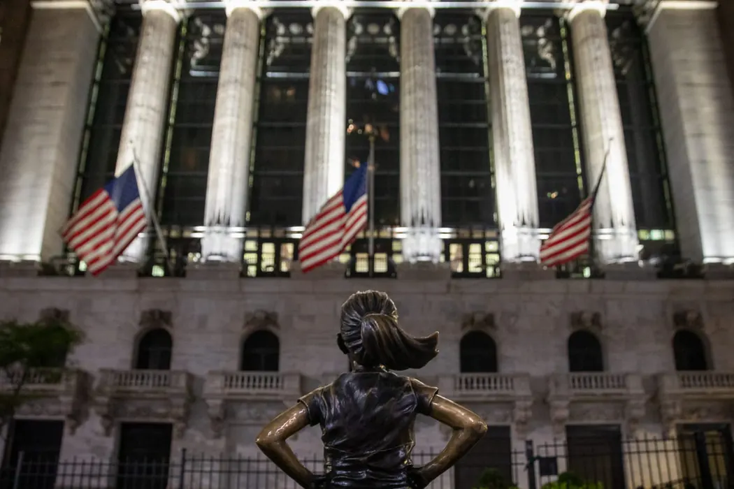 The Fearless Girl statue facing the New York Stock Exchange at night