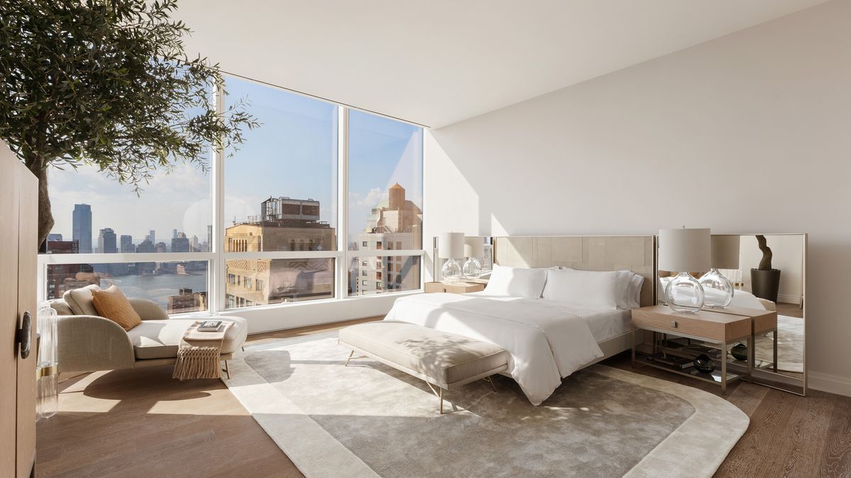 The primary bedroom with floor-to-ceiling glass and skyline views
